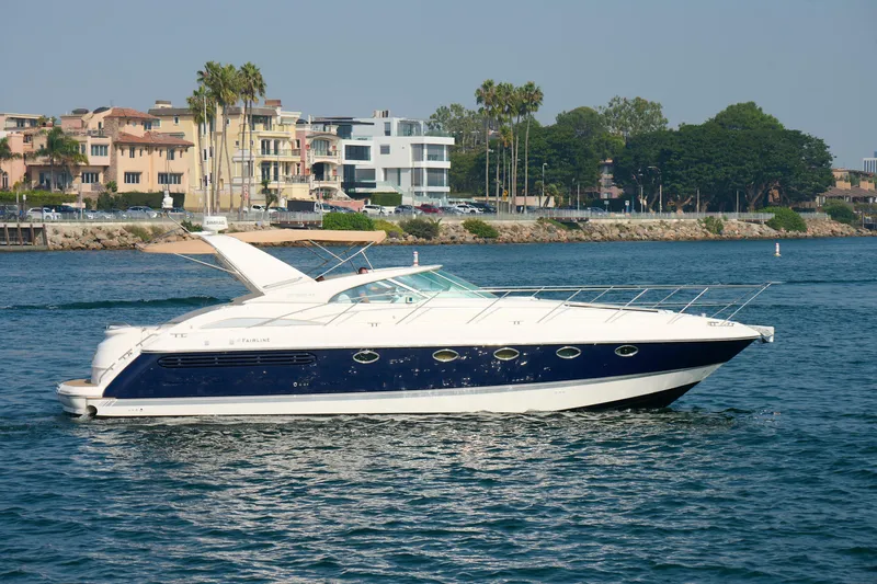 Slide: The Image of Luxury 2001 Fairline 43 yacht cruising near waterfront homes and palm trees. - 4