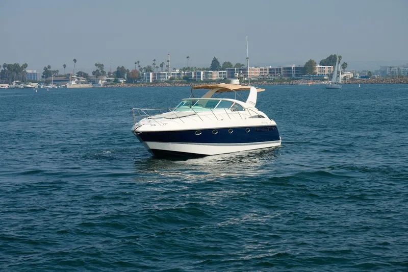 Slide: The Image of 2001 Fairline 43 yacht cruising on calm waters near a coastal cityscape. - 6
