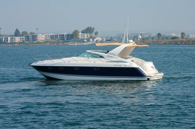 Slide: The Image of 2001 Fairline 43 yacht cruising on calm waters near a coastal cityscape. - 7
