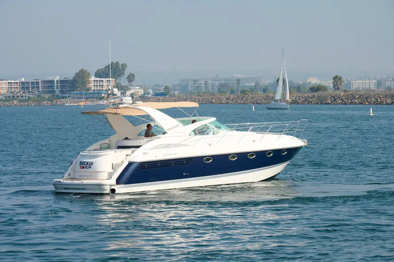 Slide: The Image of 2001 Fairline 43 yacht cruising on calm waters with cityscape in background. - 8