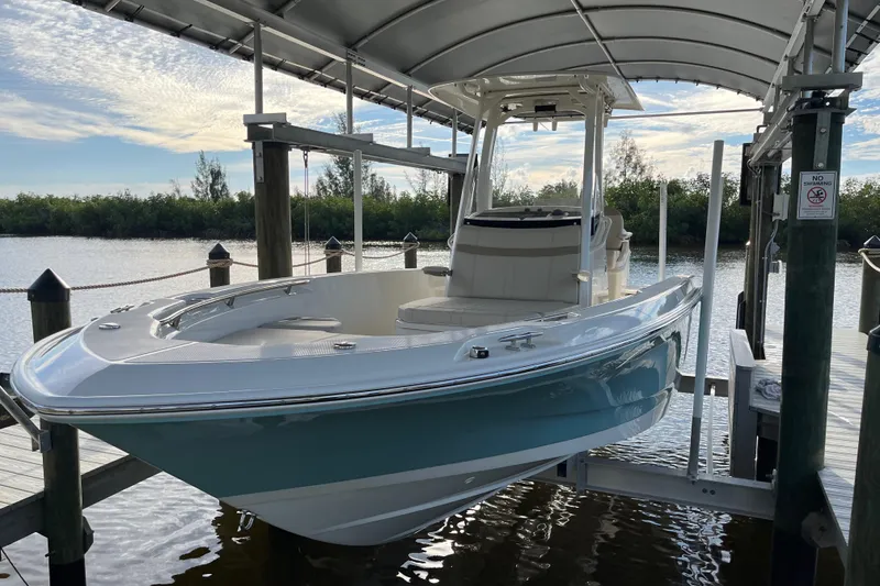 Slide: The Image of 2024 Boston Whaler 250 Dauntless boat docked under a canopy on a sunny day. - 2