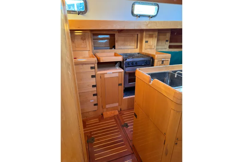 Slide: The Image of Interior of 2007 Chuck Burns Custom 49' Schooner, featuring wooden cabinetry and compact kitchen. - 39