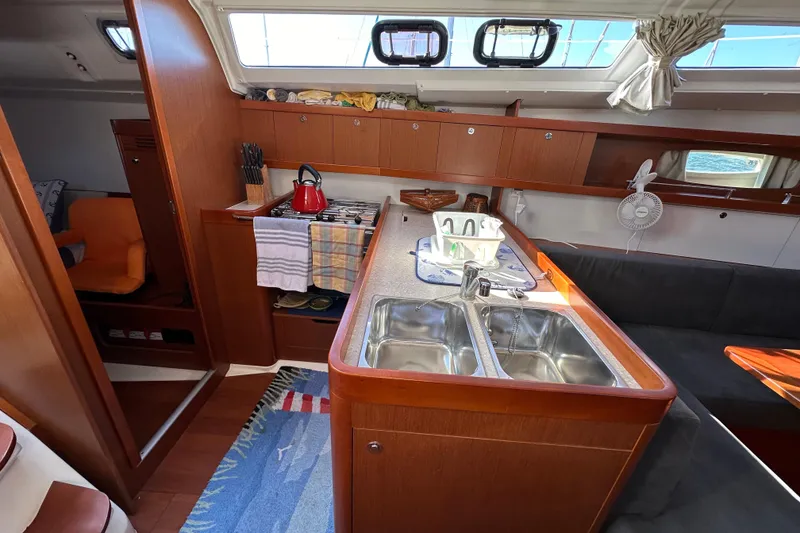 Slide: The Image of Interior of 2015 Beneteau Oceanis 37 yacht, featuring a cozy kitchen and seating area. - 18