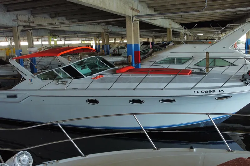 Slide: The Image of 1993 Wellcraft 4300 Portofino yacht with red canopy docked in a covered marina. - 8