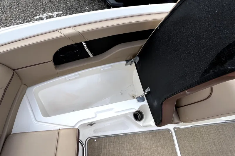 Slide: The Image of 2016 Sea Ray 220 Sundeck interior storage compartment with beige seating and open hatch. - 10