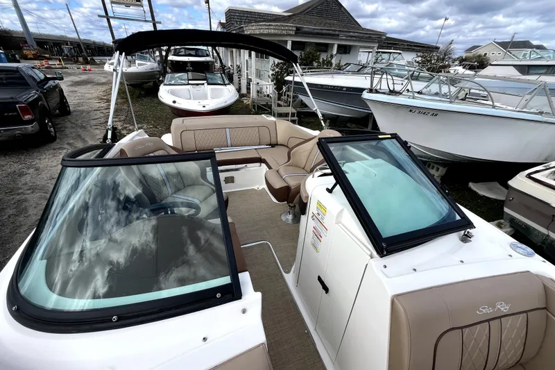 Slide: The Image of 2016 Sea Ray 220 Sundeck boat with beige seating, docked among other boats. - 11
