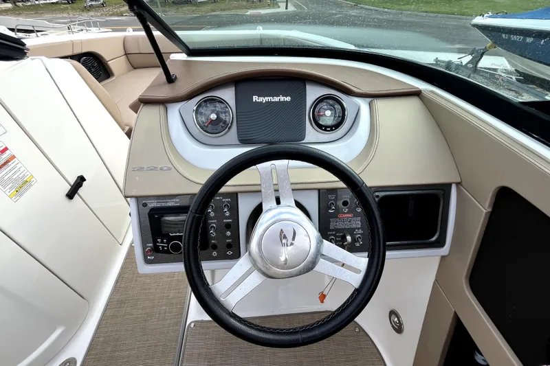 Slide: The Image of 2016 Sea Ray 220 Sundeck boat dashboard with steering wheel and Raymarine display. - 14