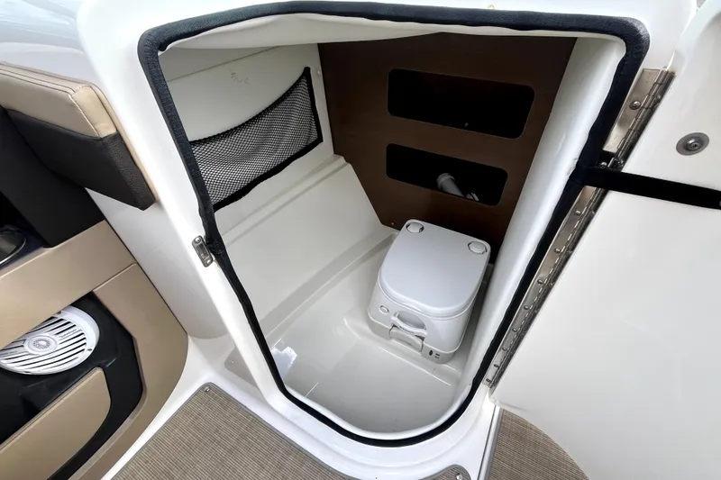 Slide: The Image of Interior of 2016 Sea Ray 220 Sundeck showing compact marine toilet and storage. - 16