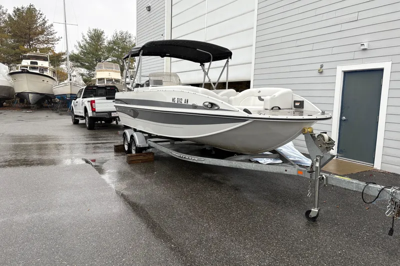 Slide: The Image of 2022 Princecraft Ventura 224 boat on trailer, parked near a building on a rainy day. - 2