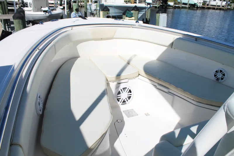 Slide: The Image of 2016 Robalo R300 Center Console boat with spacious seating and speakers, docked by the water. - 12