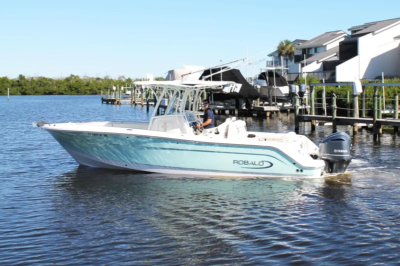Slide: The Image of 2016 Robalo R300 Center Console boat cruising on a sunny day near docks. - 3