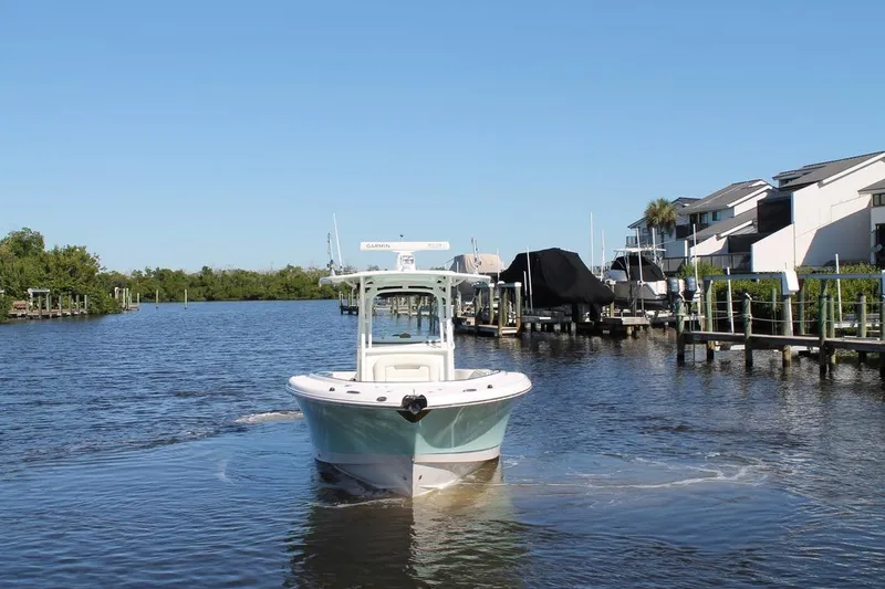 Slide: The Image of 2016 Robalo R300 Center Console boat navigating a calm marina channel. - 6