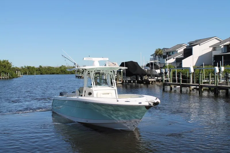 Slide: The Image of 2016 Robalo R300 Center Console boat on a scenic waterfront near docks. - 7