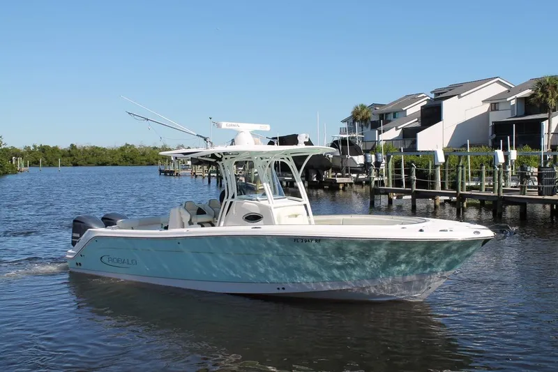 Slide: The Image of 2016 Robalo R300 Center Console boat on a sunny waterfront with modern buildings. - 8