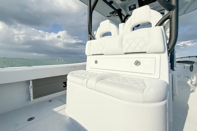 Slide: The Image of 2026 Yellowfin 34 Offshore boat interior with white seating, ocean view, and cloudy sky. - 8