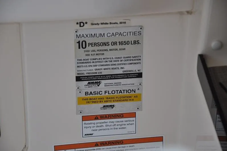 Slide: The Image of Capacity label on 2022 Grady-White Freedom 235 boat, detailing maximum weight and safety warnings. - 35