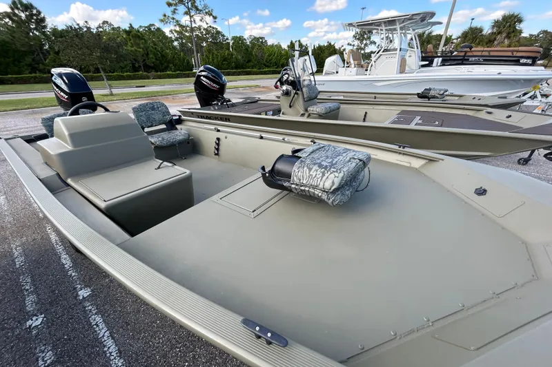 Slide: The Image of 2026 Tracker Grizzly 1754 SC boat with camouflage seats, parked outdoors. - 2