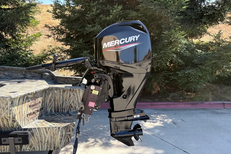 Slide: The Image of 2026 Tracker Grizzly 1650 T Prairie Wings Edition with Mercury outboard motor, parked outdoors. - 10