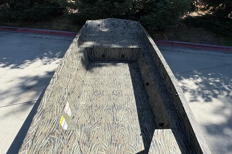 Slide: The Image of 2026 Tracker Grizzly 1650 T Prairie Wings Edition boat with camouflage design on pavement. - 16
