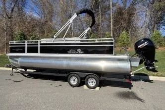 Slide: The Image of 2026 Sun Tracker Fishin' Barge 22 DLX pontoon boat on trailer, parked outdoors. - 73