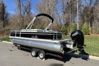 Slide: The Image of 2026 Sun Tracker Fishin' Barge 22 DLX pontoon boat on trailer, parked outdoors. - 74