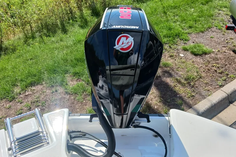 Slide: The Image of 2026 Tahoe T21 boat with Mercury 100 outboard motor, parked on grassy area. - 2