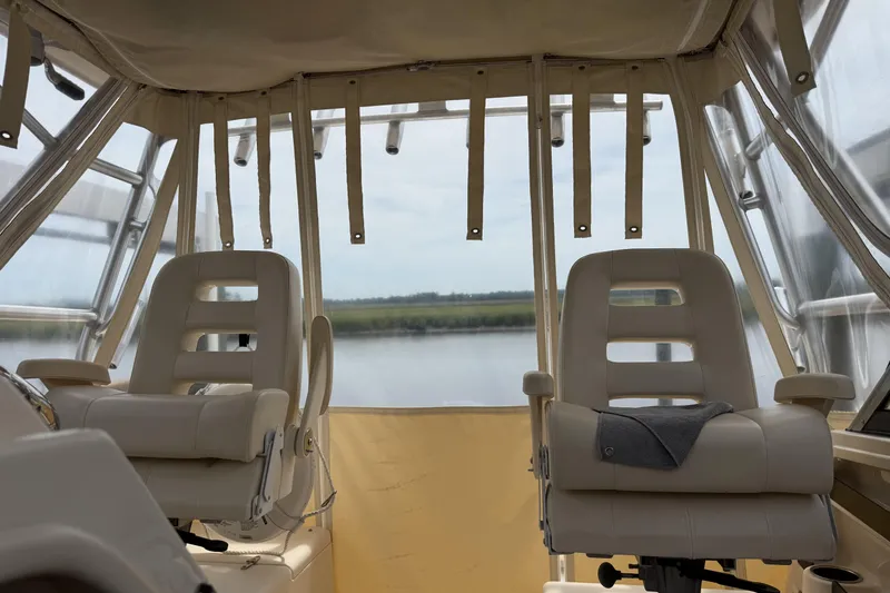 Slide: The Image of 2015 Grady-White Marlin 300 boat interior with seating and helm, docked outdoors. - 7