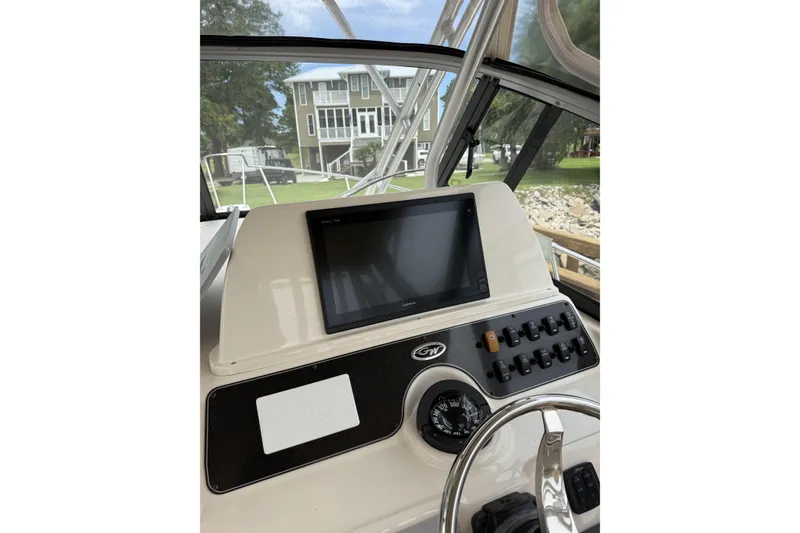 Slide: The Image of 2015 Grady-White Marlin 300 boat cockpit with rod holders, set against a forest backdrop. - 8