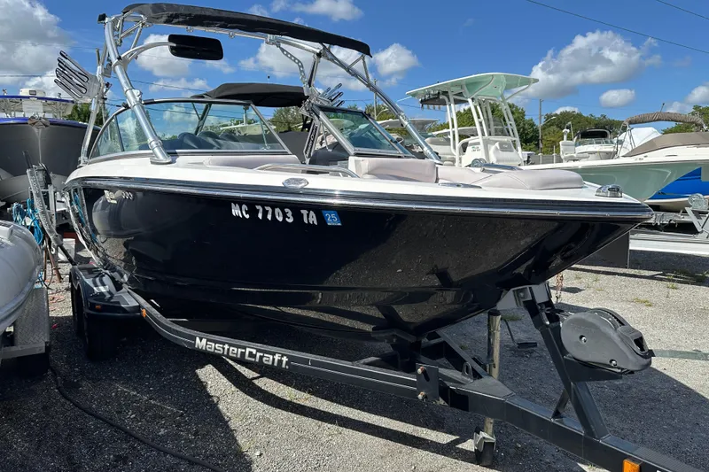 The Image of 2007 MasterCraft X-15 boat on trailer, parked outdoors under blue sky. - 0