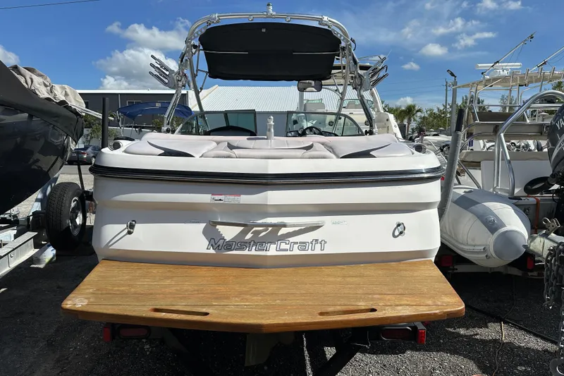 Slide: The Image of 2007 MasterCraft X-15 boat with wooden swim platform, parked outdoors under a clear sky. - 3