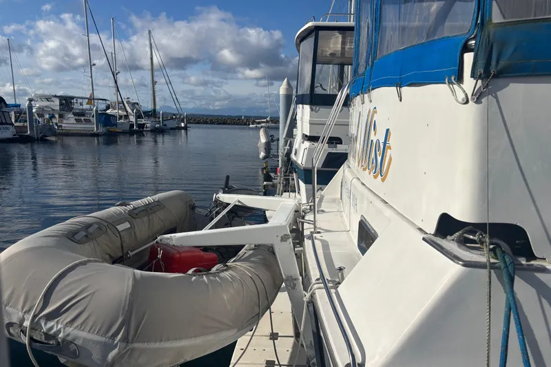 Slide: The Image of 1986 Ponderosa boat docked with inflatable dinghy, marina background, cloudy sky. - 15