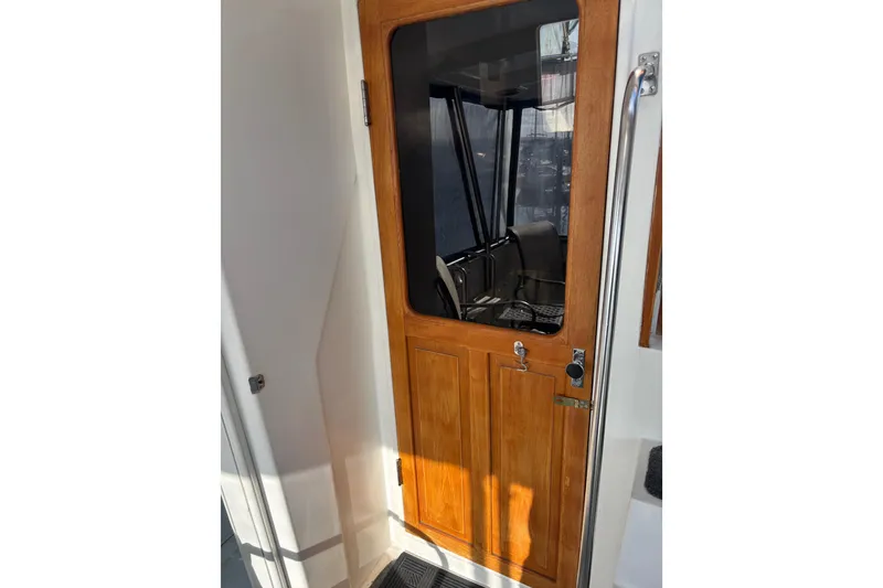 Slide: The Image of Wooden door on 1986 Ponderosa boat, featuring glass window and metal handle. - 17