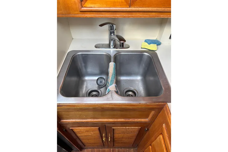 Slide: The Image of Stainless steel double sink with faucet, wooden cabinets, and cleaning sponges, Ponderosa 1986. - 35