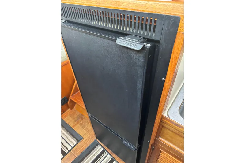 Slide: The Image of 1986 Ponderosa boat interior with Nova Kool refrigerator, wooden cabinetry, and striped rug. - 36