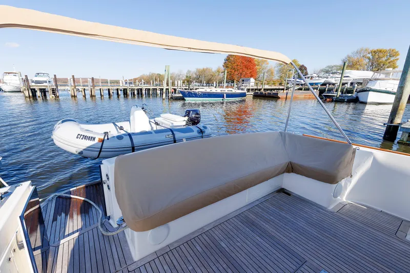 Slide: The Image of 2019 Grand Banks 44 Eastbay SX yacht with tender at marina, featuring spacious deck seating. - 10