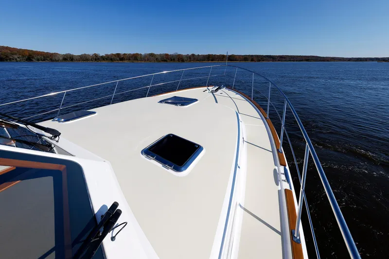 Slide: The Image of 2019 Grand Banks 44 Eastbay SX yacht cruising on a serene lake under clear blue skies. - 17