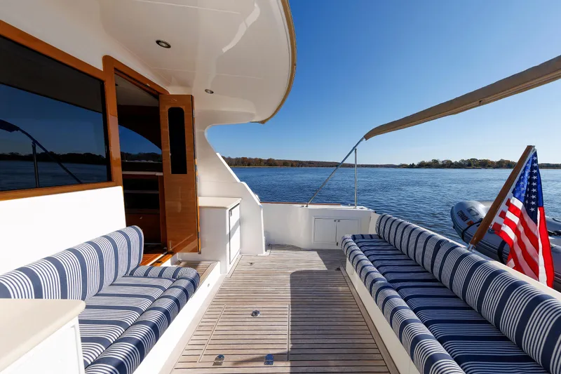 Slide: The Image of 2019 Grand Banks 44 Eastbay SX yacht deck with striped seating and American flag. - 22