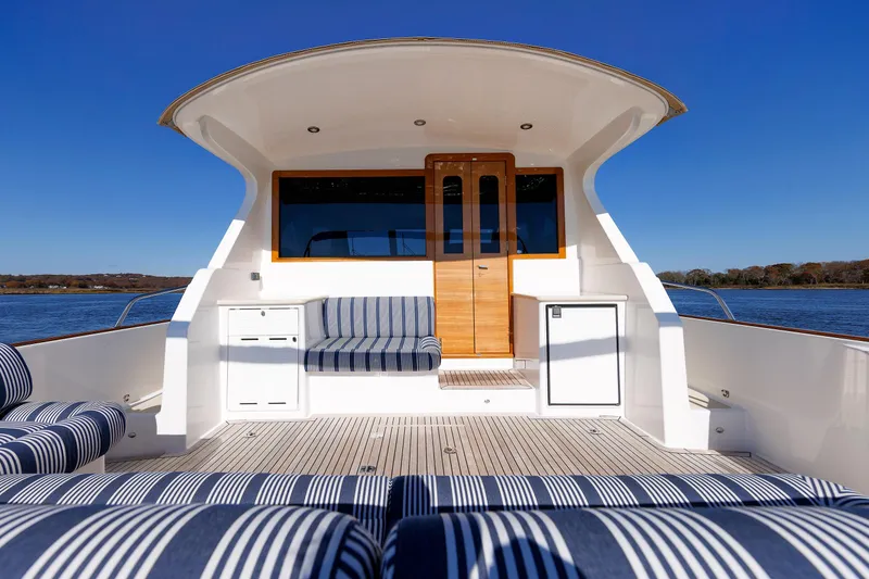 Slide: The Image of 2019 Grand Banks 44 Eastbay SX yacht with striped seating, wooden door, and ocean view. - 24