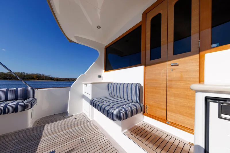 Slide: The Image of 2019 Grand Banks 44 Eastbay SX yacht deck with striped seating and wooden doors. - 26