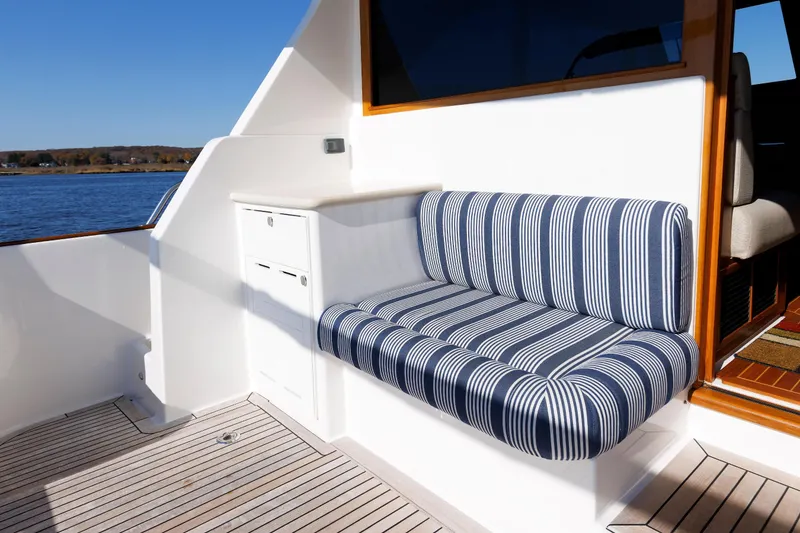 Slide: The Image of Striped seating on 2019 Grand Banks 44 Eastbay SX yacht deck, overlooking serene water. - 28