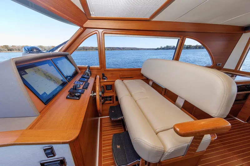 Slide: The Image of 2019 Grand Banks 44 Eastbay SX helm with leather seating and navigation screens, overlooking serene waters. - 4