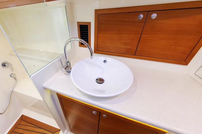 Slide: The Image of Luxury bathroom sink on 2019 Grand Banks 44 Eastbay SX yacht, featuring elegant wood cabinetry. - 48