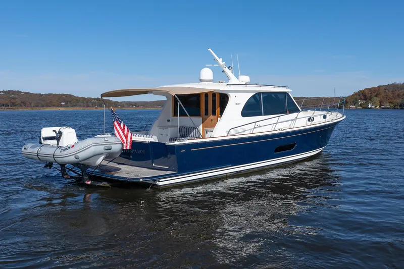 Slide: The Image of 2019 Grand Banks 44 Eastbay SX yacht on calm water, featuring sleek design and American flag. - 7