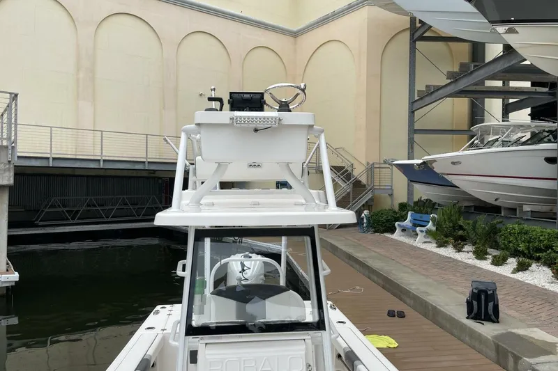 Slide: The Image of 2022 Robalo 246 Cayman SD boat docked in a marina with other vessels. - 27