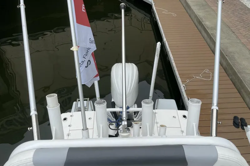 Slide: The Image of 2022 Robalo 246 Cayman SD boat docked, featuring rod holders and a flag. - 39