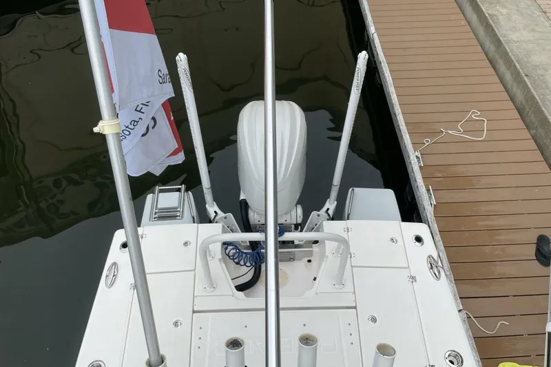 Slide: The Image of 2022 Robalo 246 Cayman SD boat docked, rear view with flag and motor visible. - 40