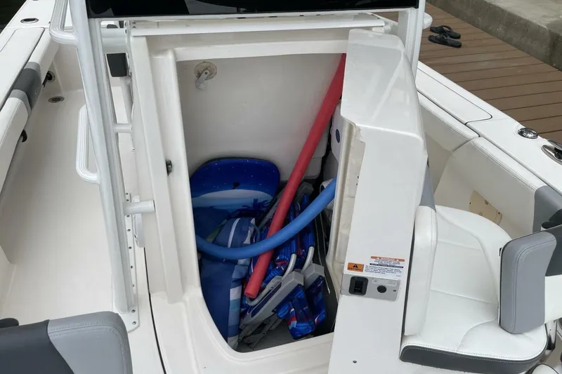 Slide: The Image of 2022 Robalo 246 Cayman SD boat storage compartment with pool noodles and beach gear. - 43