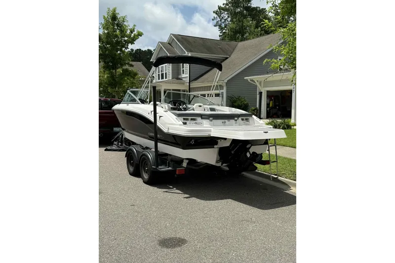 Slide: The Image of 2021 Chaparral 216 SSi boat with open bow seating, parked on a residential street. - 3