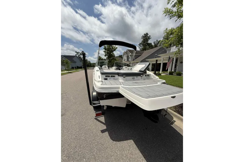 Slide: The Image of 2021 Chaparral 216 SSi boat parked on a residential street under a partly cloudy sky. - 6