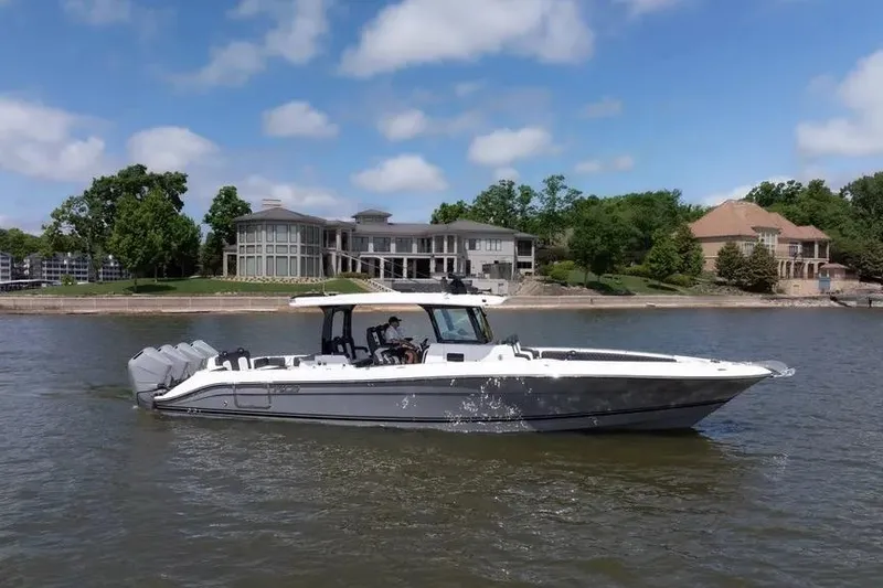 The Image of 2024 HCB 42 Lujo boat cruising on a lake with luxury homes in the background. - 0